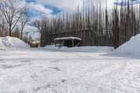 a fence is surrounded by snow outside in the winter in front of a house and some trees