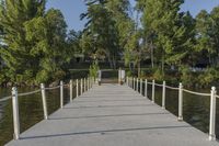 a pier at the edge of a body of water with trees in the background and bushes