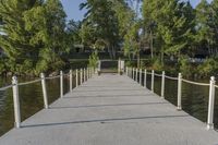 a pier at the edge of a body of water with trees in the background and bushes