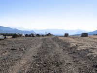 a dirt road in the middle of some rocks and a mountain range in the distance