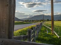 a lone country road is in the countryside area with mountains on both sides and barbed fence between the two sides