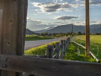 a lone country road is in the countryside area with mountains on both sides and barbed fence between the two sides