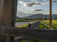 a lone country road is in the countryside area with mountains on both sides and barbed fence between the two sides