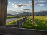 a lone country road is in the countryside area with mountains on both sides and barbed fence between the two sides