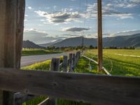 a lone country road is in the countryside area with mountains on both sides and barbed fence between the two sides