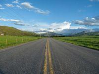 a lone country road is in the countryside area with mountains on both sides and barbed fence between the two sides