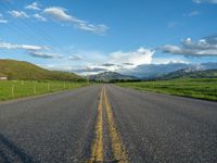 a lone country road is in the countryside area with mountains on both sides and barbed fence between the two sides