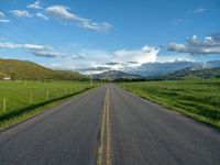 a lone country road is in the countryside area with mountains on both sides and barbed fence between the two sides