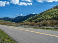 the road is paved with yellow markings and has a snowy mountain range in the background