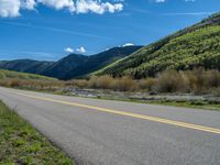 the road is paved with yellow markings and has a snowy mountain range in the background