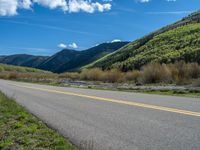 the road is paved with yellow markings and has a snowy mountain range in the background