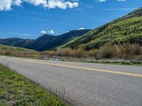 the road is paved with yellow markings and has a snowy mountain range in the background