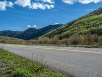 the road is paved with yellow markings and has a snowy mountain range in the background