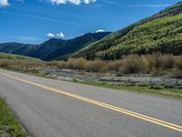 the road is paved with yellow markings and has a snowy mountain range in the background