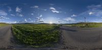 a view from a vehicle on the road towards a green field of grass and mountains