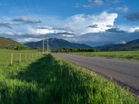 a lone country road is in the countryside area with mountains on both sides and barbed fence between the two sides