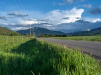 a lone country road is in the countryside area with mountains on both sides and barbed fence between the two sides