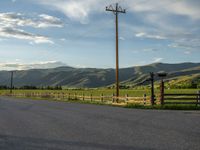 a lone country road is in the countryside area with mountains on both sides and barbed fence between the two sides