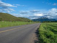 a lone country road is in the countryside area with mountains on both sides and barbed fence between the two sides