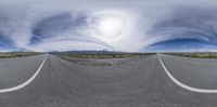 a fish eye view looking down an empty road at mountains and clouds with a sky full of grayish waves