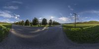 an empty road that is surrounded by trees and grass is shown through a fisheye lens