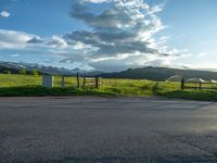 a lone country road is in the countryside area with mountains on both sides and barbed fence between the two sides