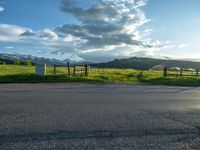 a lone country road is in the countryside area with mountains on both sides and barbed fence between the two sides