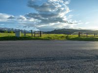 a lone country road is in the countryside area with mountains on both sides and barbed fence between the two sides