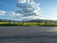 a lone country road is in the countryside area with mountains on both sides and barbed fence between the two sides