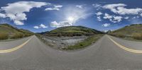 there is a fish eye view of the road in the picture and the hills with rocks in front