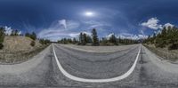 an empty highway is wide and straight with trees on either side of the road and sun shining above