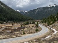 a mountain side with a road running next to the mountains, a bike parked in front of it and trees on one side