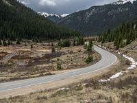 a mountain side with a road running next to the mountains, a bike parked in front of it and trees on one side