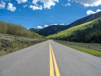 the road is paved with yellow markings and has a snowy mountain range in the background