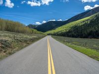 the road is paved with yellow markings and has a snowy mountain range in the background