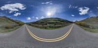 a curved road stretching into the distance and a blue sky with white clouds above it