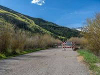 an open gate sits behind a warning sign on the side of the road that's blocked off