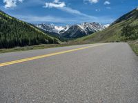 the road is paved with yellow markings and has a snowy mountain range in the background