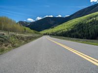 the road is paved with yellow markings and has a snowy mountain range in the background