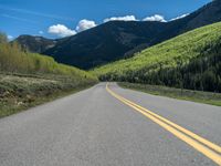 the road is paved with yellow markings and has a snowy mountain range in the background