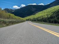 the road is paved with yellow markings and has a snowy mountain range in the background