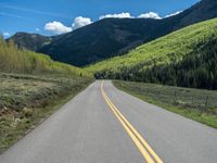 the road is paved with yellow markings and has a snowy mountain range in the background