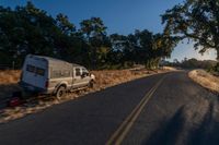 cars are driving down a paved street near the tall grass fields on an empty street