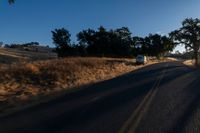 cars are driving down a paved street near the tall grass fields on an empty street