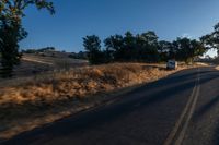 cars are driving down a paved street near the tall grass fields on an empty street