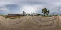 a camera panoramic view of a rural dirt road and farm area with buildings