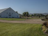 an image of a farm with many horses in the back yard and lawn area in front of them