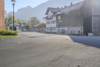 a person riding their horse down the street in front of a building and mountains behind