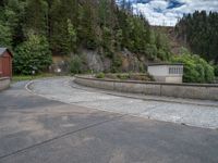 concrete walkway with trees and fenced in area on opposite sides of the road and one side of the road