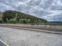 concrete walkway with trees and fenced in area on opposite sides of the road and one side of the road